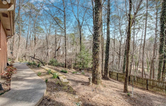 view of yard featuring a forest view and fence