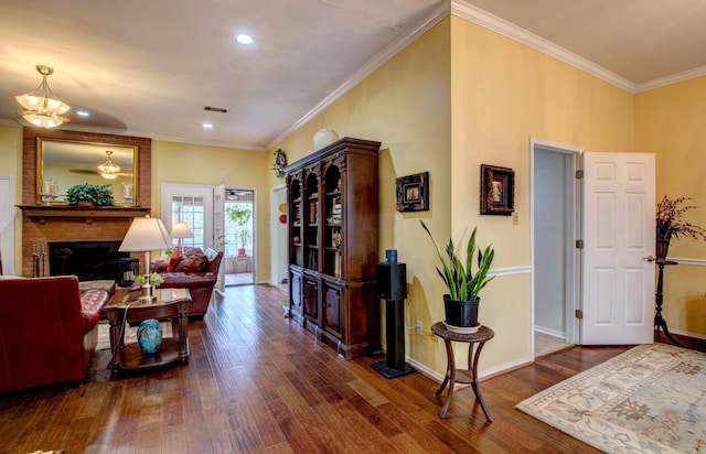 living area with baseboards, a brick fireplace, hardwood / wood-style flooring, and crown molding