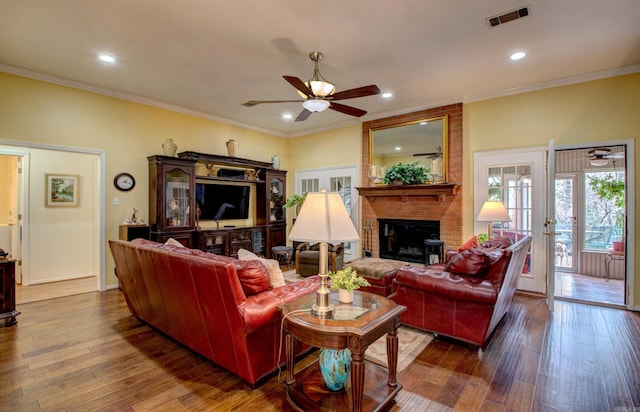 living area with ornamental molding, hardwood / wood-style floors, visible vents, and a ceiling fan