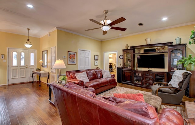 living area featuring a ceiling fan, wood-type flooring, visible vents, and crown molding