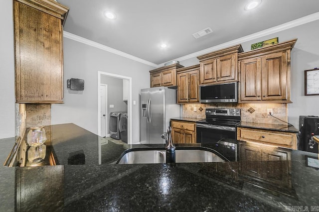 kitchen with appliances with stainless steel finishes, ornamental molding, a sink, separate washer and dryer, and backsplash