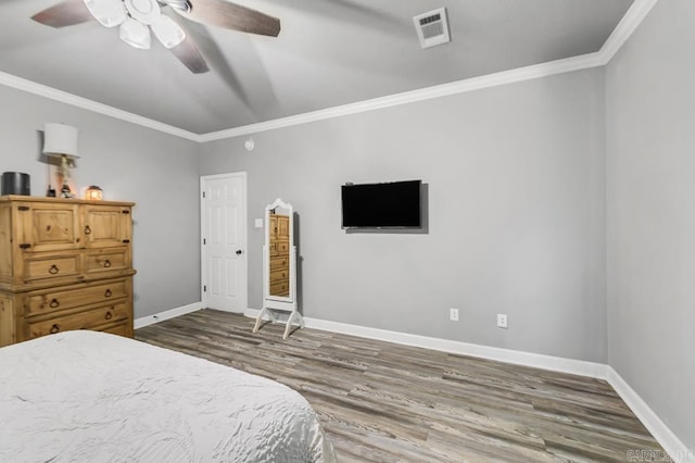 bedroom featuring ornamental molding, visible vents, baseboards, and wood finished floors