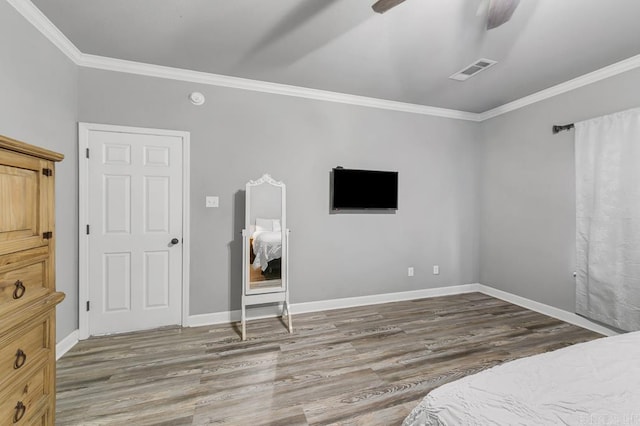 bedroom with ceiling fan, wood finished floors, visible vents, baseboards, and ornamental molding