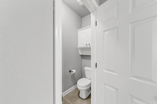 bathroom with tile patterned flooring, baseboards, and toilet
