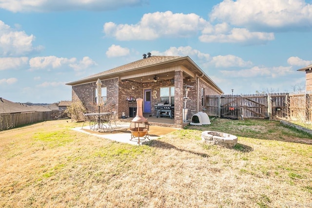 rear view of property featuring ceiling fan, a fire pit, a fenced backyard, and a patio
