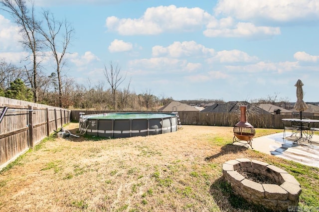 view of yard with a fenced in pool, a patio area, a fenced backyard, and a fire pit