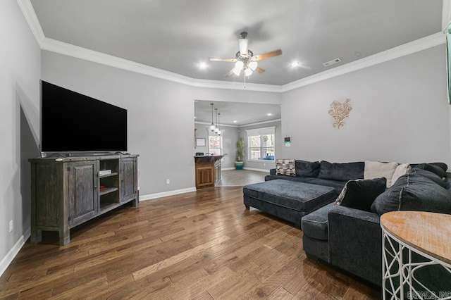 living area with ceiling fan with notable chandelier, wood finished floors, visible vents, baseboards, and ornamental molding