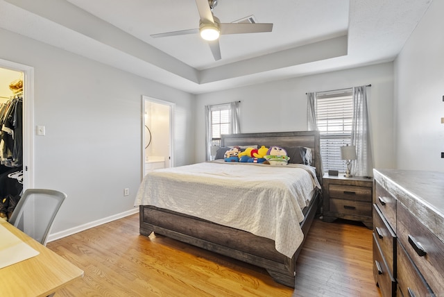 bedroom with baseboards, a raised ceiling, and wood finished floors