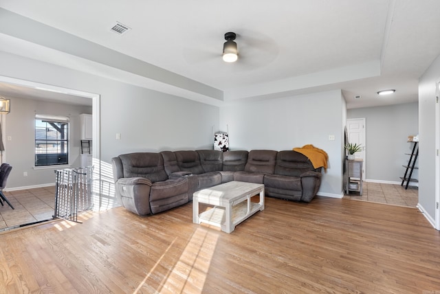 living area with light wood finished floors, baseboards, visible vents, and a ceiling fan