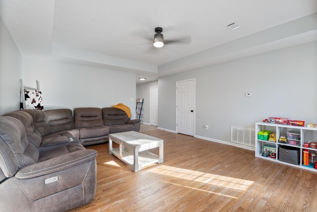 living area featuring a ceiling fan, light wood-type flooring, visible vents, and baseboards