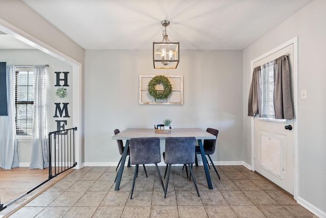 dining space with an inviting chandelier, baseboards, and light tile patterned floors