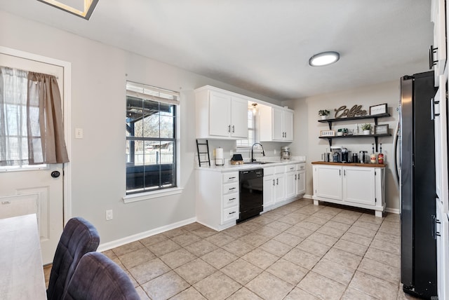 kitchen with a sink, white cabinetry, dishwasher, and freestanding refrigerator