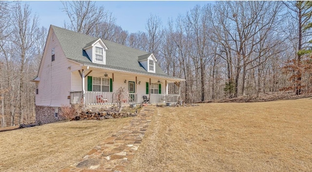 cape cod-style house featuring a ceiling fan, a front yard, covered porch, and roof with shingles