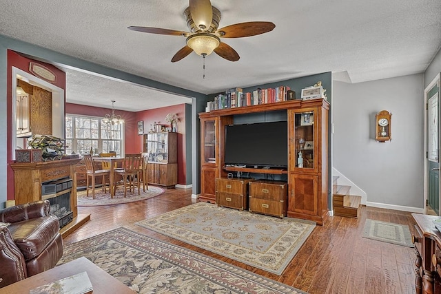 living room with stairway, ceiling fan with notable chandelier, a textured ceiling, and hardwood / wood-style flooring