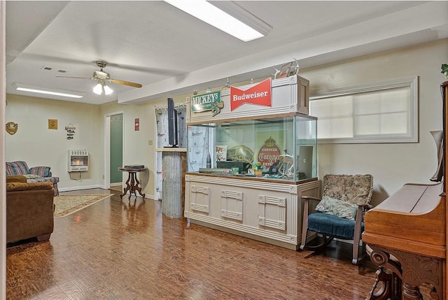 interior space with heating unit, visible vents, a ceiling fan, wood finished floors, and baseboards