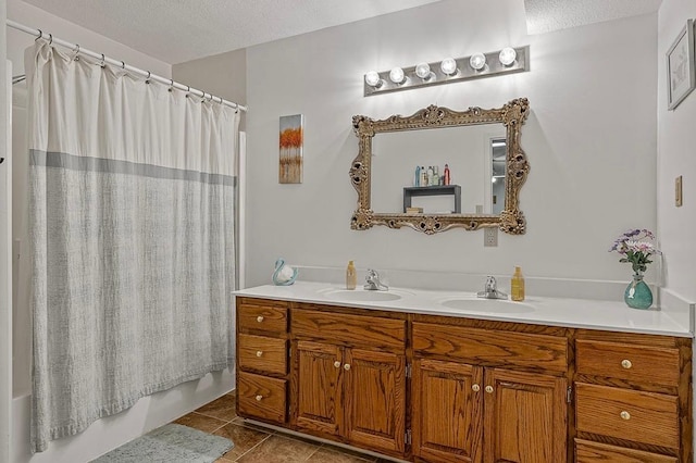 bathroom with a textured ceiling, double vanity, tile patterned flooring, and a sink