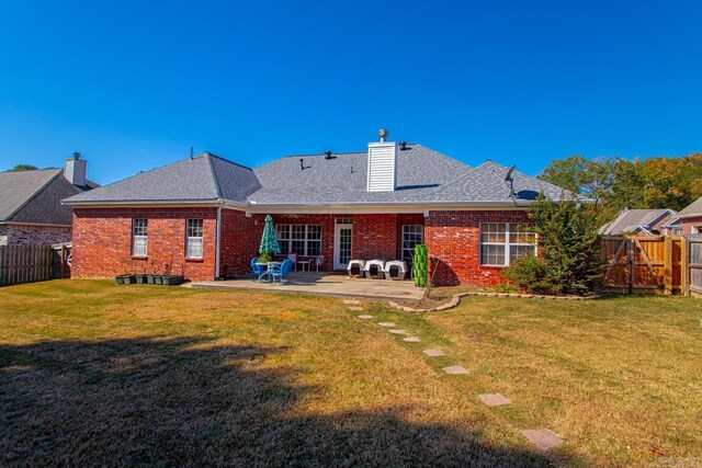 rear view of house with a patio area, brick siding, and a fenced backyard