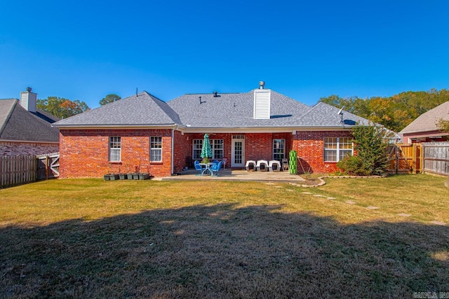 rear view of house featuring a yard, brick siding, and a fenced backyard