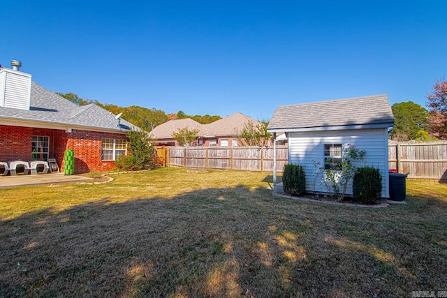 view of yard with a fenced backyard, an outdoor structure, and a storage unit