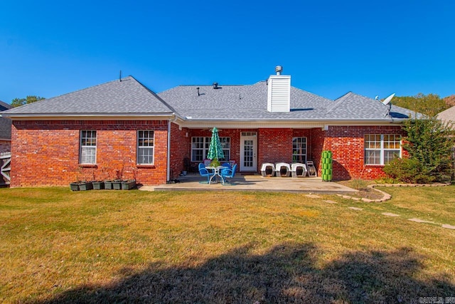 back of house featuring a yard, brick siding, and a patio area