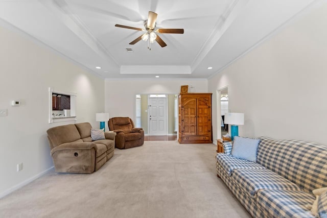 living area with light carpet, a raised ceiling, crown molding, and recessed lighting