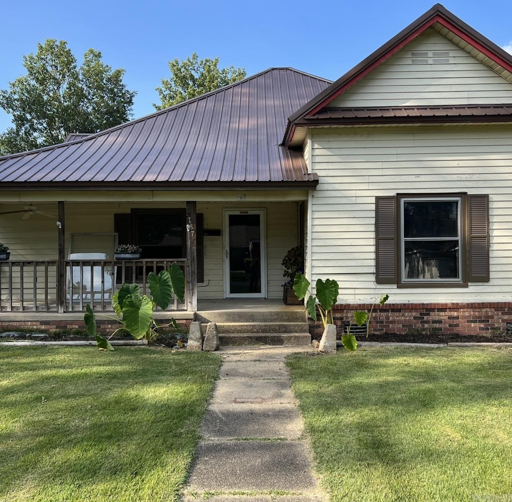 view of front of house with covered porch, metal roof, and a front yard