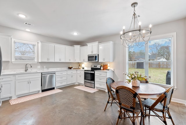 kitchen with stainless steel appliances, light countertops, visible vents, white cabinetry, and a sink