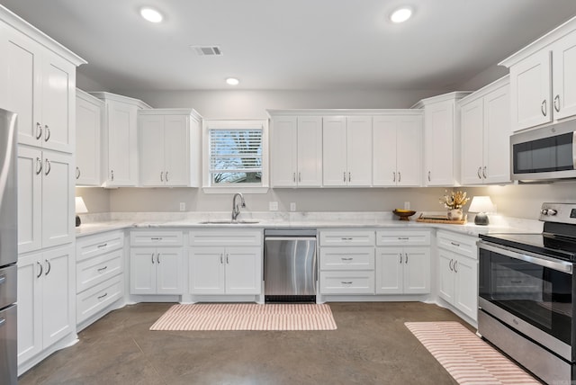 kitchen with finished concrete floors, white cabinetry, stainless steel appliances, and a sink