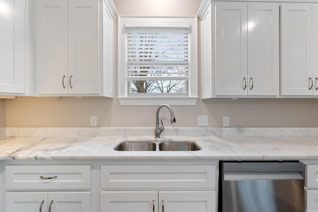 kitchen featuring white cabinets, a sink, stainless steel dishwasher, and light stone countertops