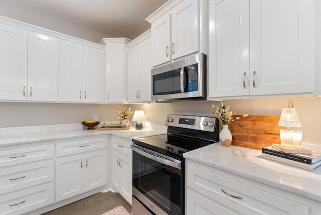 kitchen with appliances with stainless steel finishes, light stone counters, and white cabinets