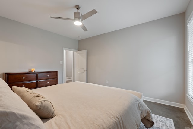 bedroom with multiple windows, dark carpet, a ceiling fan, and baseboards