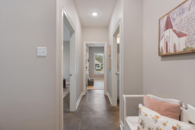 hallway featuring concrete floors and baseboards