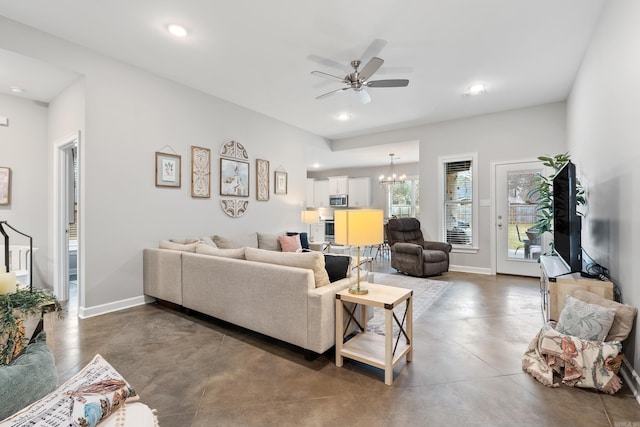 living room featuring baseboards, concrete floors, ceiling fan with notable chandelier, and recessed lighting