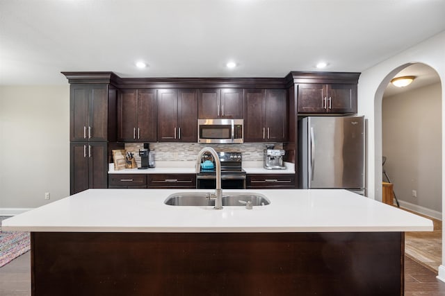 kitchen with decorative backsplash, stainless steel appliances, dark brown cabinets, light countertops, and a sink