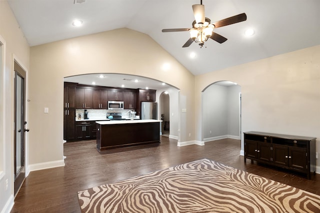 kitchen featuring dark brown cabinetry, arched walkways, appliances with stainless steel finishes, dark wood-style flooring, and light countertops