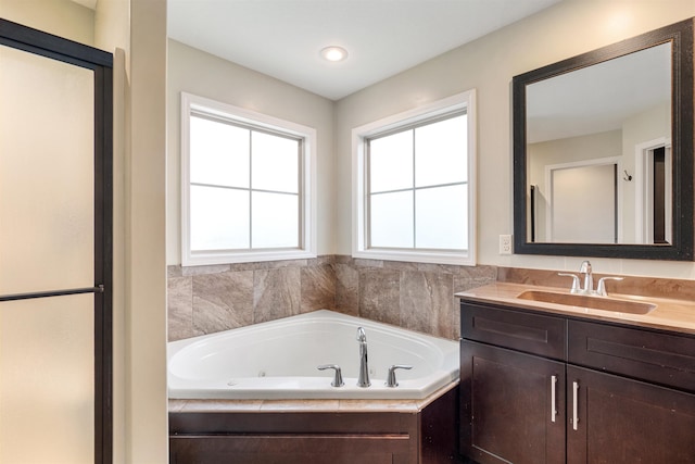 bathroom with a tub with jets and vanity