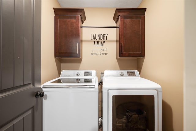 clothes washing area featuring washing machine and dryer and cabinet space