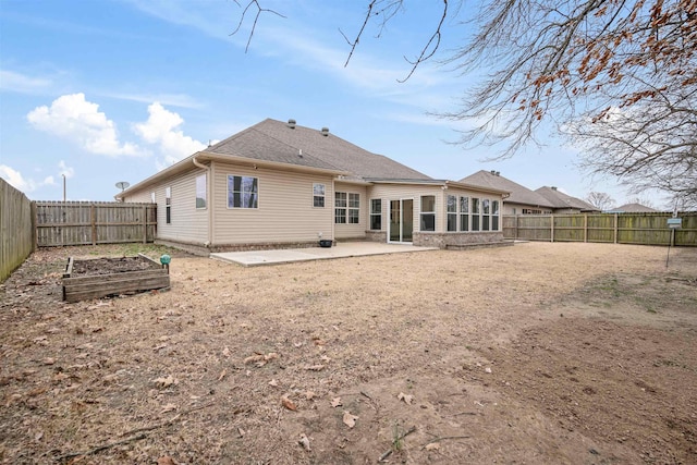 rear view of house with a patio, a shingled roof, a fenced backyard, and a vegetable garden