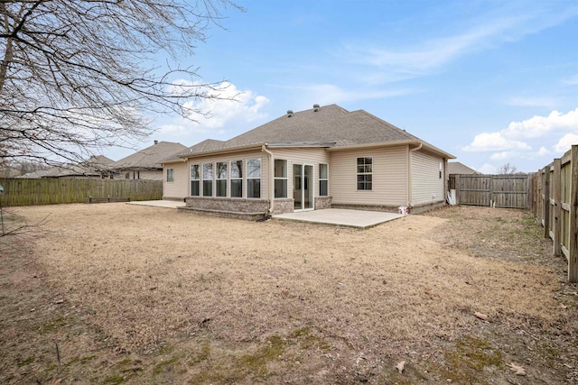 rear view of property featuring a patio, roof with shingles, and a fenced backyard