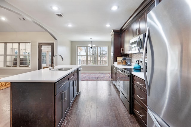 kitchen with stainless steel appliances, visible vents, a sink, and dark brown cabinetry