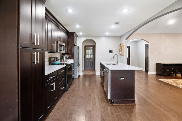 kitchen featuring visible vents, arched walkways, dark wood-style floors, stainless steel appliances, and a sink