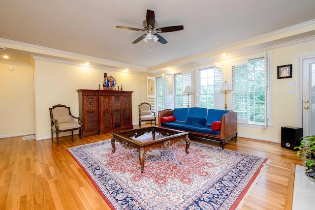 living room featuring ceiling fan, ornamental molding, light wood-type flooring, and baseboards