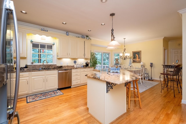 kitchen featuring light wood-style flooring, a kitchen island, a kitchen breakfast bar, stainless steel appliances, and crown molding