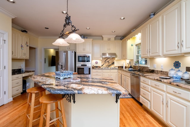 kitchen featuring crown molding, appliances with stainless steel finishes, light wood-style floors, a sink, and under cabinet range hood