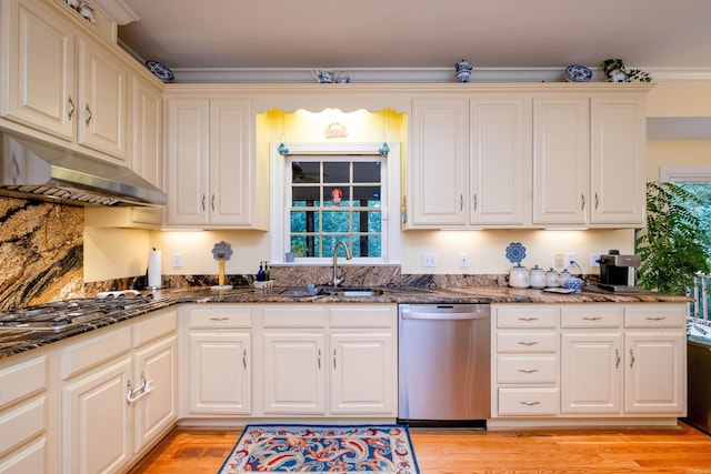 kitchen featuring under cabinet range hood, a sink, gas stovetop, light wood-type flooring, and dishwasher