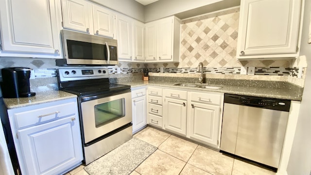 kitchen featuring stainless steel appliances, backsplash, a sink, and white cabinets