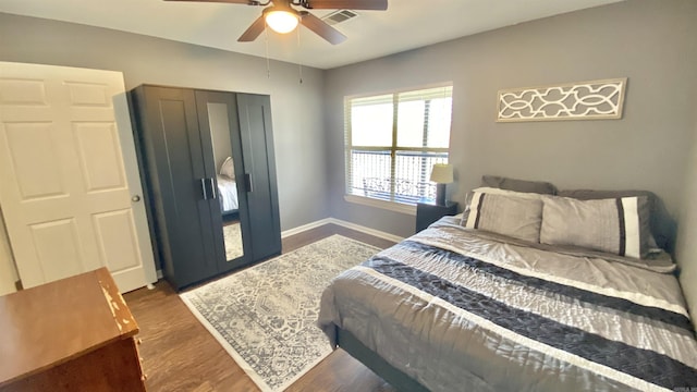 bedroom with a ceiling fan, baseboards, visible vents, and wood finished floors