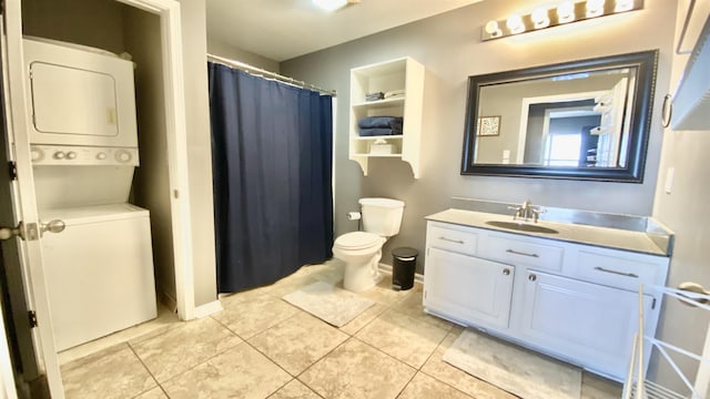 bathroom featuring stacked washer and clothes dryer, toilet, vanity, baseboards, and tile patterned floors