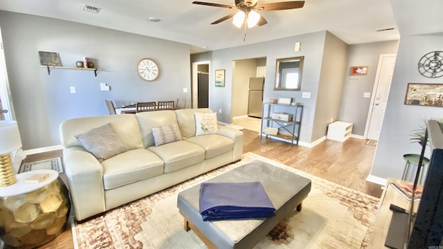 living area with baseboards, visible vents, ceiling fan, and wood finished floors