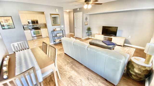 living room with ceiling fan and baseboards